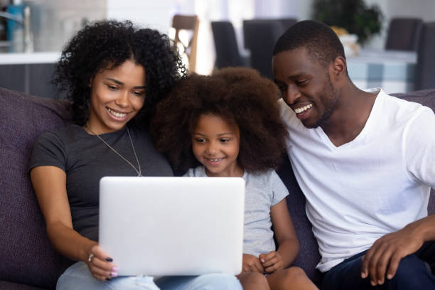 istock Happy african family with child having fun using laptop together 1126384468