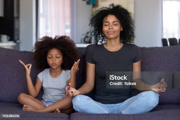 Mindful African Mom With Funny Kid Daughter Doing Yoga Together Stock Photo - Download Image Now