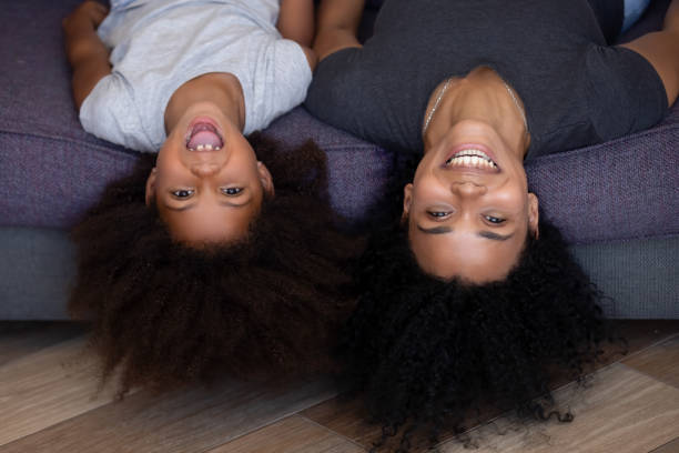 istock Happy mixed-race mother and daughter lying upside down on sofa 1126384540