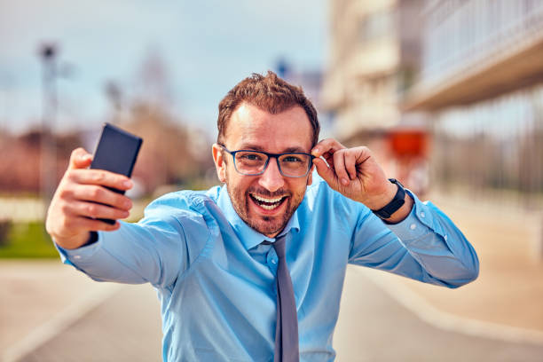 istock Funny businessman with thumbs up while using smartphone outdoors. 1126391467