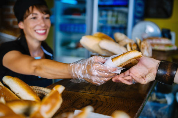 istock Smiling Baker Giving Fresh Bread To Customer At Counter In Bakery 1126395453