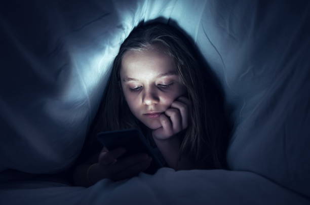 istock Girl Using Phone While Relaxing Under Blanket On Bed At Home 1126399996