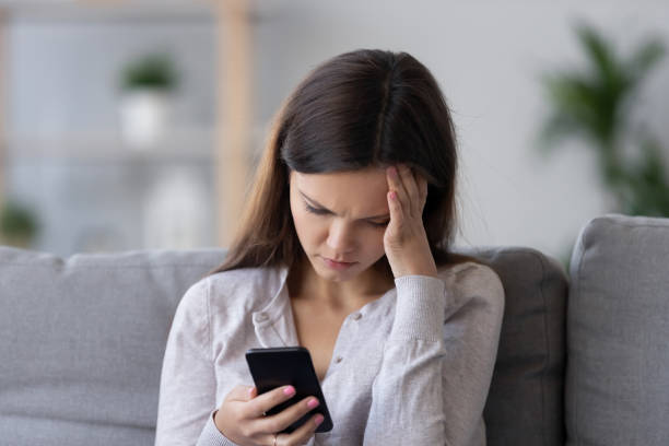 lonely sad millennial woman feeling hurt heartbroken holding phone - waiting telephone on the phone anxiety imagens e fotografias de stock