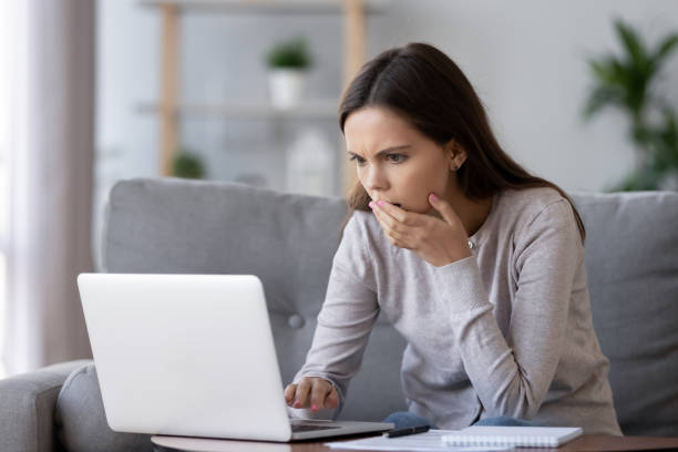 donna stressata scioccata che legge cattive notizie online guardando il laptop - complotto foto e immagini stock