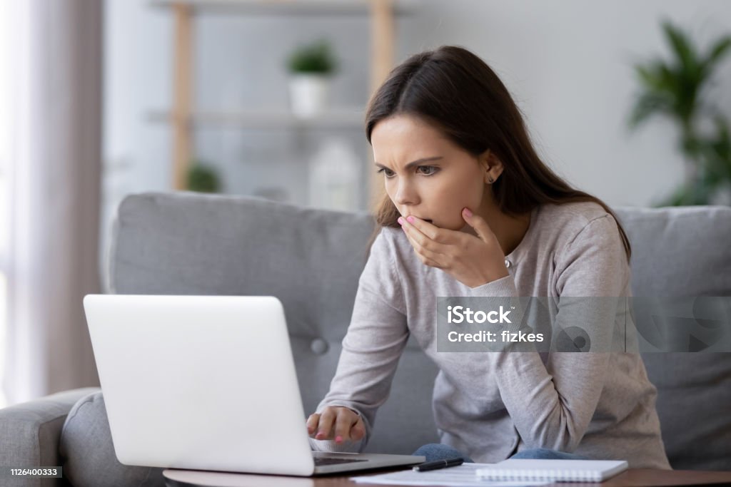 Shocked stressed woman reading bad online news looking at laptop Shocked stressed young woman reading bad online news looking at broken laptop screen, confused teen girl in panic frustrated with stuck computer problem mistake virus, negative social media message White Collar Crime Stock Photo