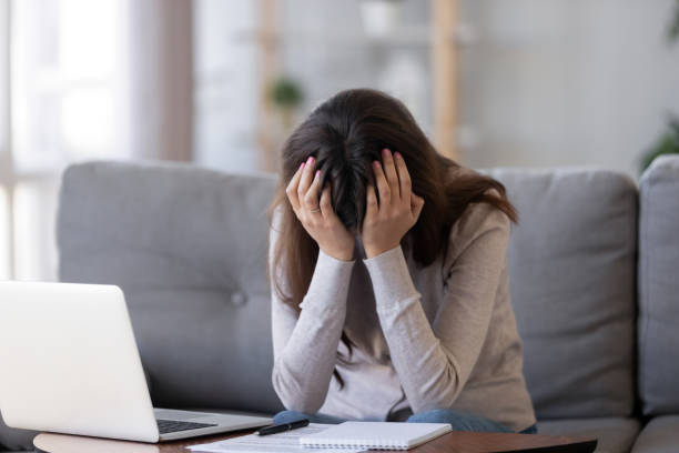 upset woman holding head in hands frustrated sitting near laptop - failure relationship difficulties computer women imagens e fotografias de stock