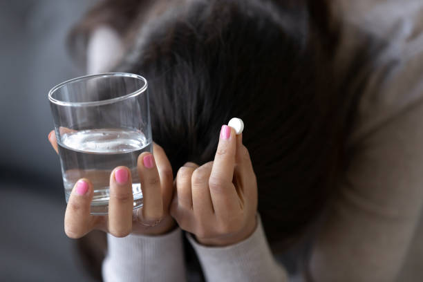 錠剤と水のガラスを保持している悲しい落ち込んでいる女性 - prozac ストックフォトと画像