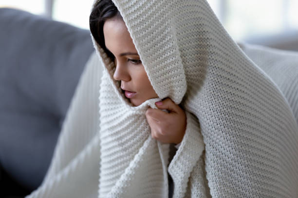 Ill young woman feeling cold having flu grippe symptoms covered with blanket, sick teen girl shivering freezing at home wrapped with plaid, no heating problem and fever temperature flue concept