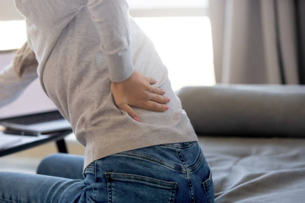 rear closeup view at woman touching aching back feeling pain - human spine posture back backache imagens e fotografias de stock