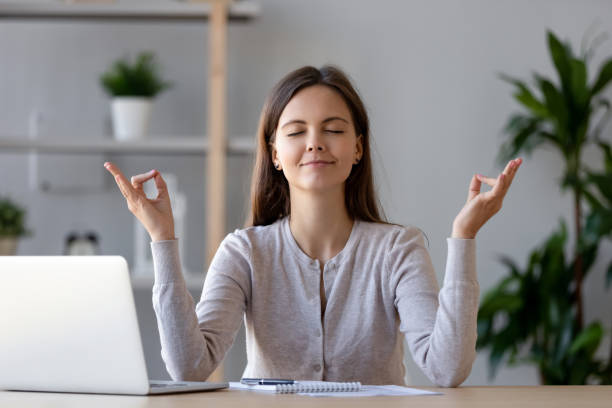 istock Calm young woman taking break doing yoga exercise at workplace 1126400376