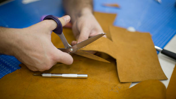 istock Man working with leather using crafting tools. Close up view of males hands cutting leather 1126402249