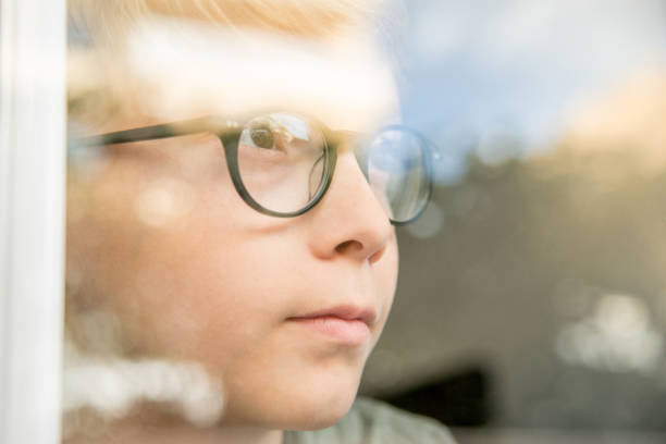 istock Close-Up Of Thoughtful Boy Looking Through Window 1126402577