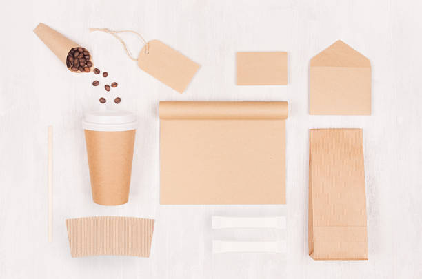 istock Decorative background for restaurant and coffee shop - blank paper cup, notebook, label, packet, coffee beans, sugar on white wood board, top view. 1126404635