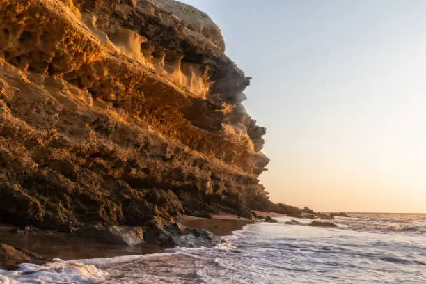Beautiful sunset on the Namibe wild beach, Africa. Angola. With cliff and rocks.