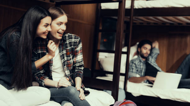 istock smiling Girls sit on bed and looking at guy 1126407554