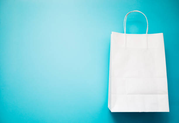 istock Eco-friendly biodegradable and compostable natural white paper bag on blue background. Flat lay mockup. Top view. 1126410159