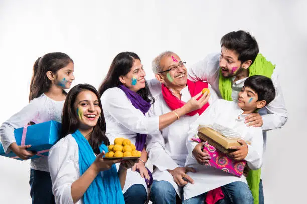 Photo of Indian Family taking selfie picture on Holi festival while holding sweets and colours