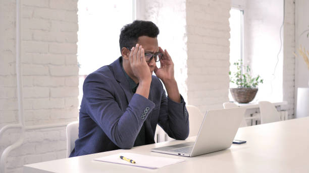 istock Headache, Stressed African Man Working on Laptop 1126411328