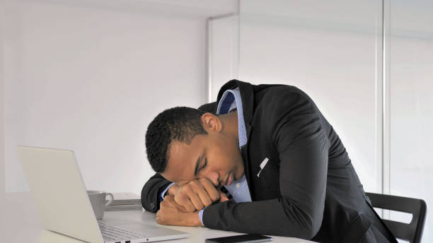 istock Sleeping African Businessman with Head on Desk at Work 1126412179