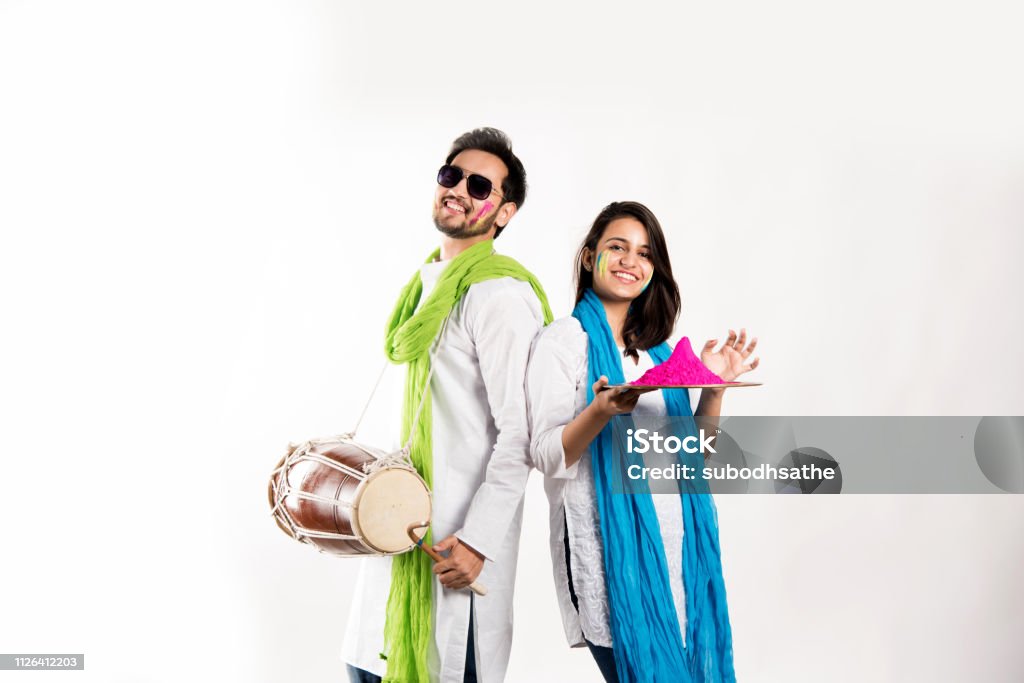 Couple jeune Indien célèbre festival de holi. Danser et jouer de la batterie et tenant l’assiette pleine de couleurs - Photo de Holi libre de droits