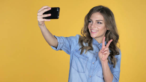 istock Young Girl Taking Selfie with Smartphone Isolated on Yellow Background 1126412404