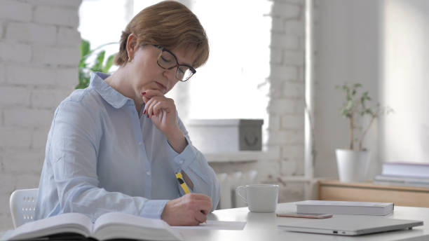 istock Pensive Old Woman Thinking and Writing, Paperwork 1126412439