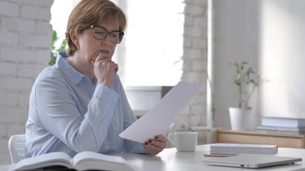istock Pensive Old Woman Reading Documents at Workplace, Brainstorming Idea 1126412447