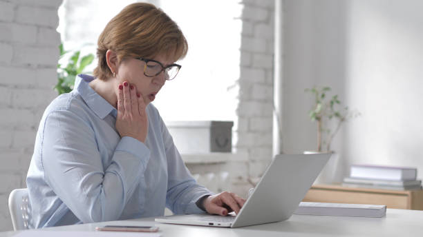 istock Old Woman with Toothache Working on Laptop 1126412568