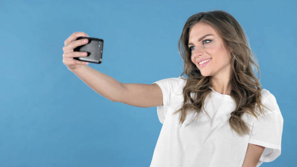 istock Young Girl Taking Selfie with Smartphone Isolated on Blue Background 1126412705