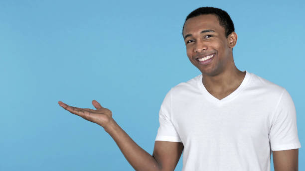 istock African Man Showing Product at Side, Blue Background 1126412815