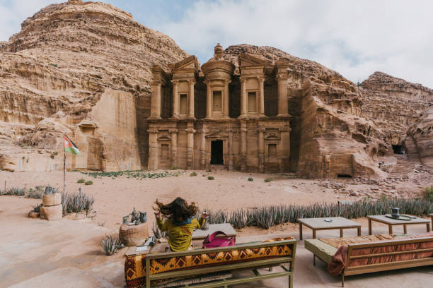 istock Woman sitting on bench  and looking at Monastery in Petra 1126414215