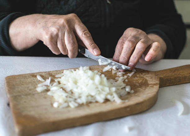 istock Hands of old woman chopping onion. selective focus. 1126418117