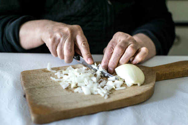 istock Hands of old woman chopping onion. selective focus. 1126418144