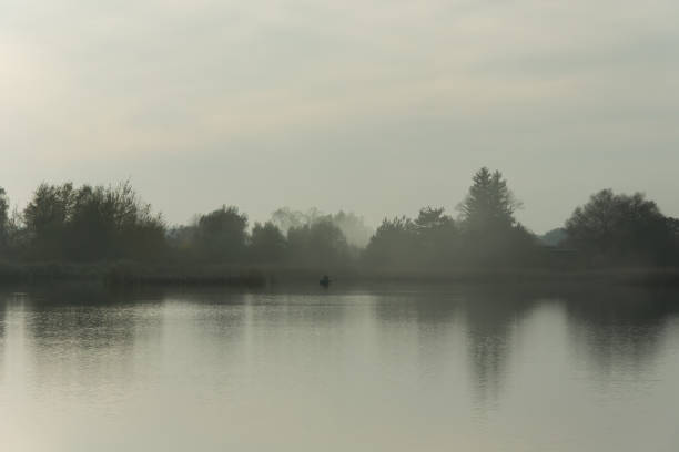 istock Fog over calm lake, angler on the boat 1126418554