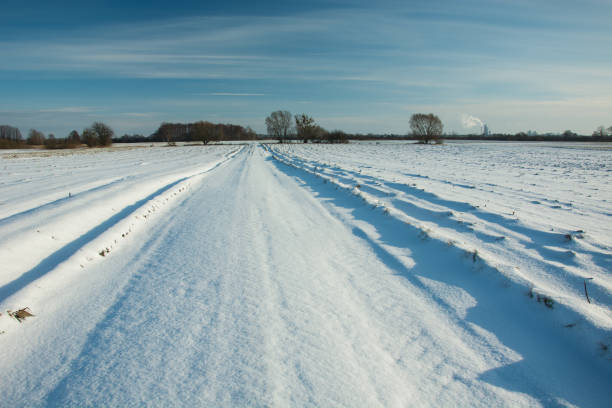 istock Road and fields covered with snow, horizon and blue sky 1126418588