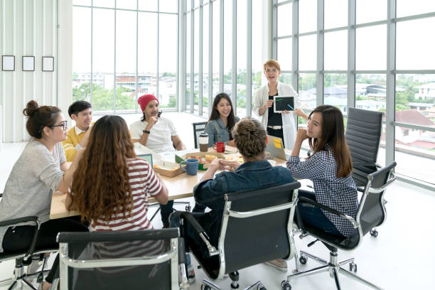 istock Young multiethnic diverse creative asian group talking or brainstorm in office meeting workshop with technology. Happy young student asian or college marketing team spend coffee break time together. 1126419431
