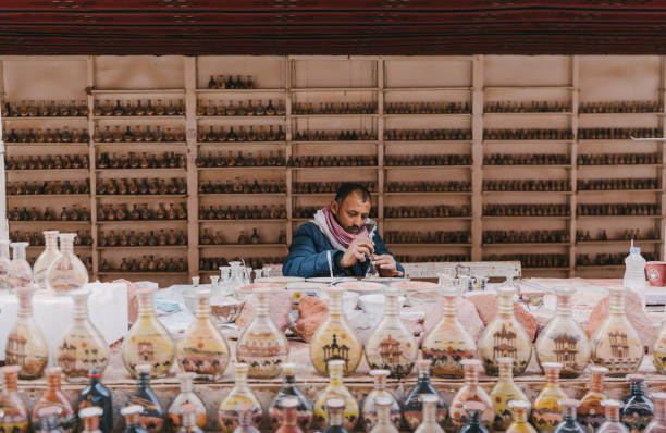 Wadi Musa, Jordan, December 12, 2018 Middle Eastern man making vases filled with sand in Petra