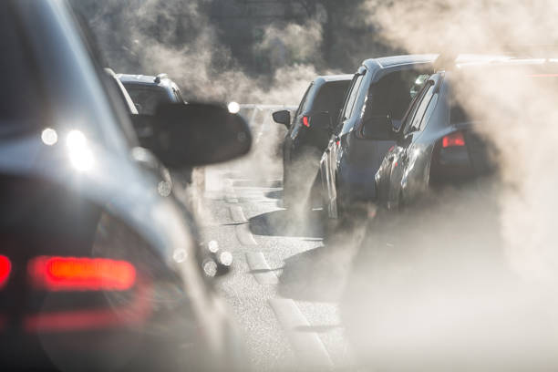 verschwommene umrisse von autos umgeben von dampf aus den auspuffrohren - pollution stock-fotos und bilder