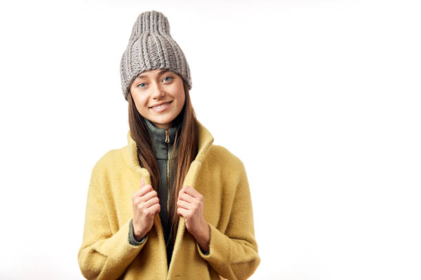 Cheerful attractive woman of european appearance wearing a lovely coat and knitted hat looking at camera with apositive smile, isolated on a white background. Women Fashion and Apparel Concept