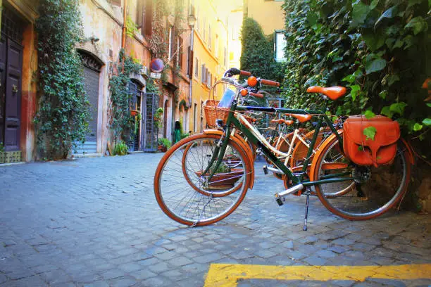 Photo of Bicycle standing in front of store on old street of Rome .