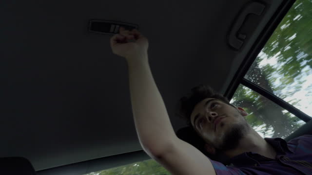 Bored teen man playing during road trip turning on and turning out the light of the car roof