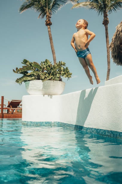 ragazzo che salta in piscina - cheerful swimming pool happiness resort swimming pool foto e immagini stock