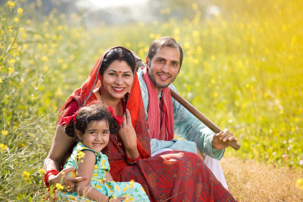 Indian family sitting on agricultural field Rural Indian family sitting together on agricultural field at village happy indian young family couple stock pictures, royalty-free photos & images