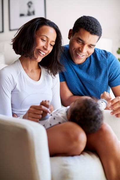 행복 한 혼합된 인종 젊은 성인 부모 그들의 3 개월 된 아기 아들을 놀고, 그의 어머니에의 무릎, 수직 - baby two parent family newborn family 뉴스 사진 이미지