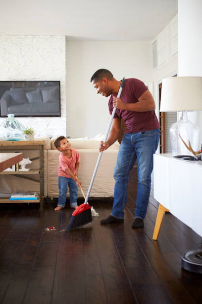 istock Grandfather and his three year old grandson looking at each other while mopping and sweeping the dining room floor, full length, vertical 1126430520