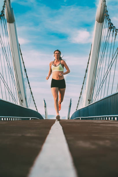 istock Young fit blonde woman running on the bridge 1126430607