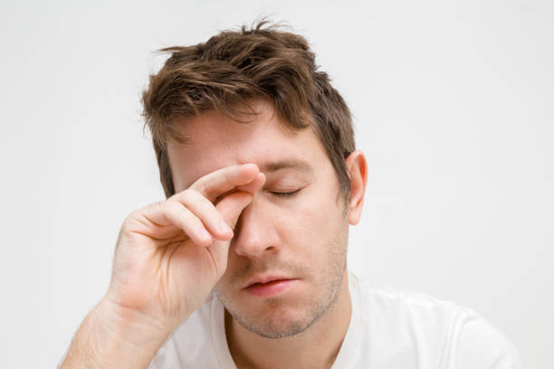 istock Young man's hand touching eye. Not getting enough sleep. Can't wake up. Men's issues. Face close up. Adult brunette guy. Isolated on gray background. 1126434112