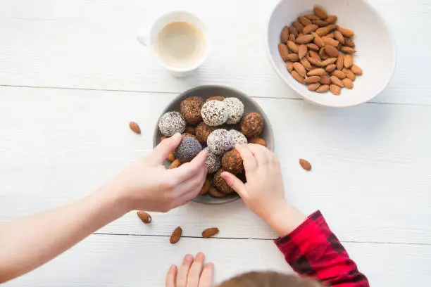 Photo of children's hands take the vegan of handmade candy on a wooden background. Fitness sweets. candies without sugar.