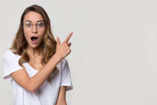istock Amazed girl wear glasses pointing at copyspace looking at camera 1126440376