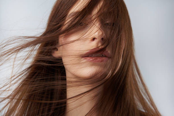 istock Young lady with hair strands on her face posing against light blue background 1126442959